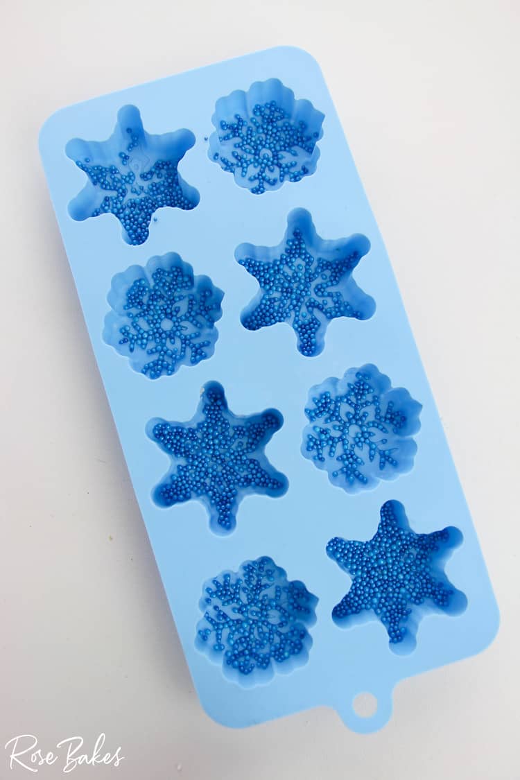 silicone snowflake mold with blue sprinkles in each cavity.