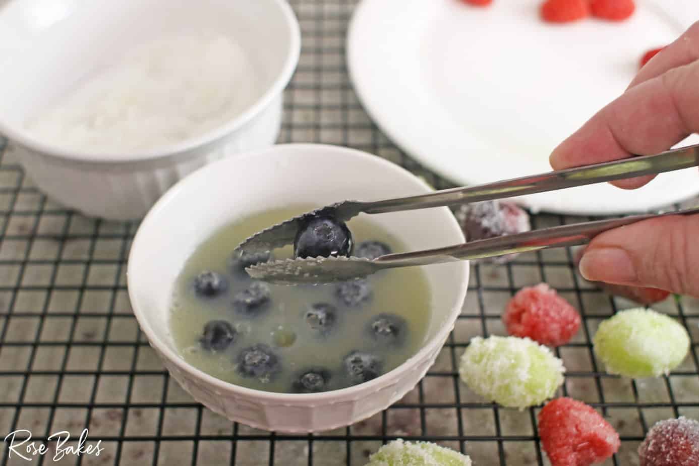 Using tongs to retrieve blueberries from the pasteurized egg whites.