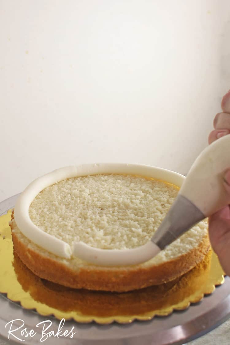 piping stiff frosting on a layer of cake