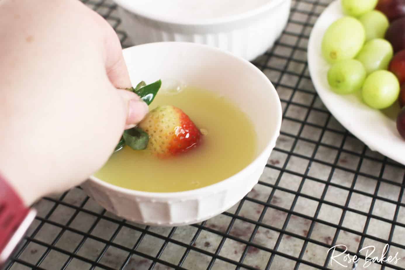Dipping a strawberry into the pasteurized egg whites.