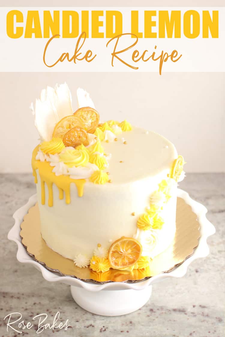 Cake frosted in white buttercream with yellow drip and yellow buttercream rosettes and stars around the top left and front right of the cake.  Among the buttercream decorations are candied lemons and white chocolate fans.  The cake is displayed on a white cake stand with a large ruffled edge.  Text at the top of the image reads, "Candied Lemon Cake Recipe"