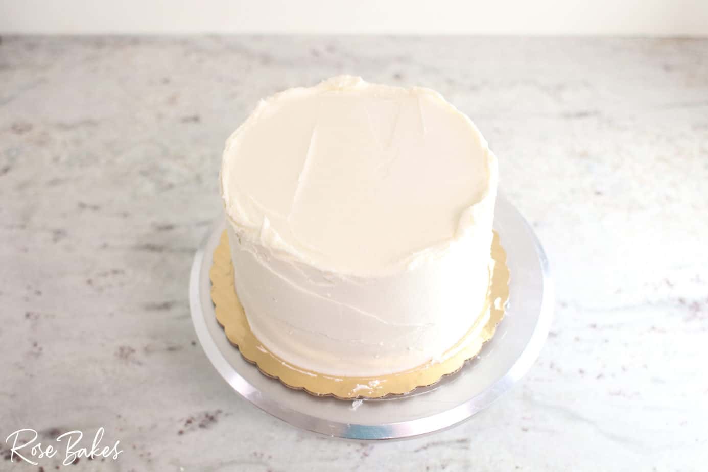 bottom tier of buttercream icing cake completed but not yet smooth 