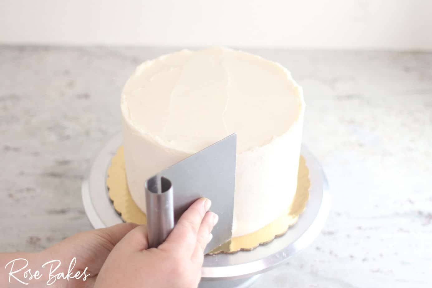 benchscraper smoothing bottom tier of cake  for the sharp edge look 