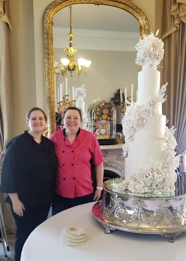 9 tier tall elegant luxury wedding cake with sugar flowers and Rose Atwater baker standing next to