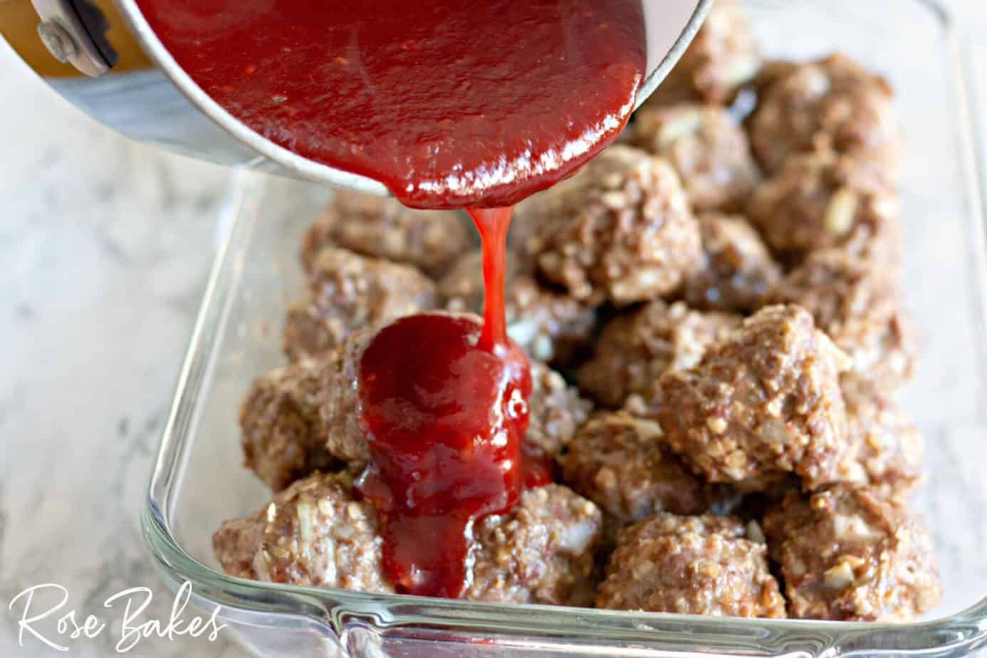 BBQ sauce being poured over the cooked meatballs