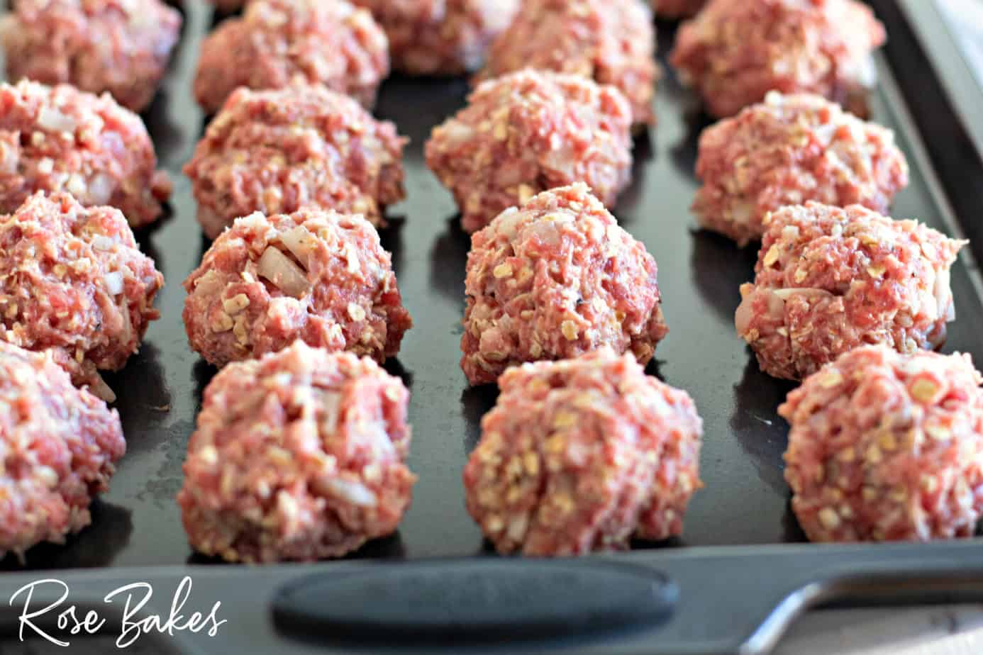 Uncooked meatballs rolled out and placed on a baking sheet