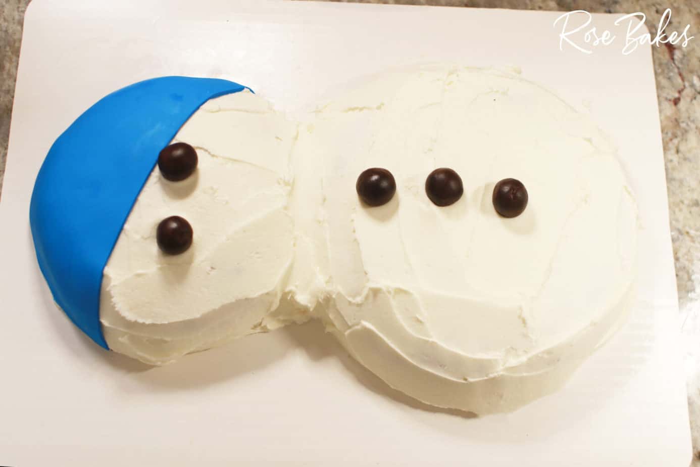 buttons and eyes added to honey coconut snowman cake