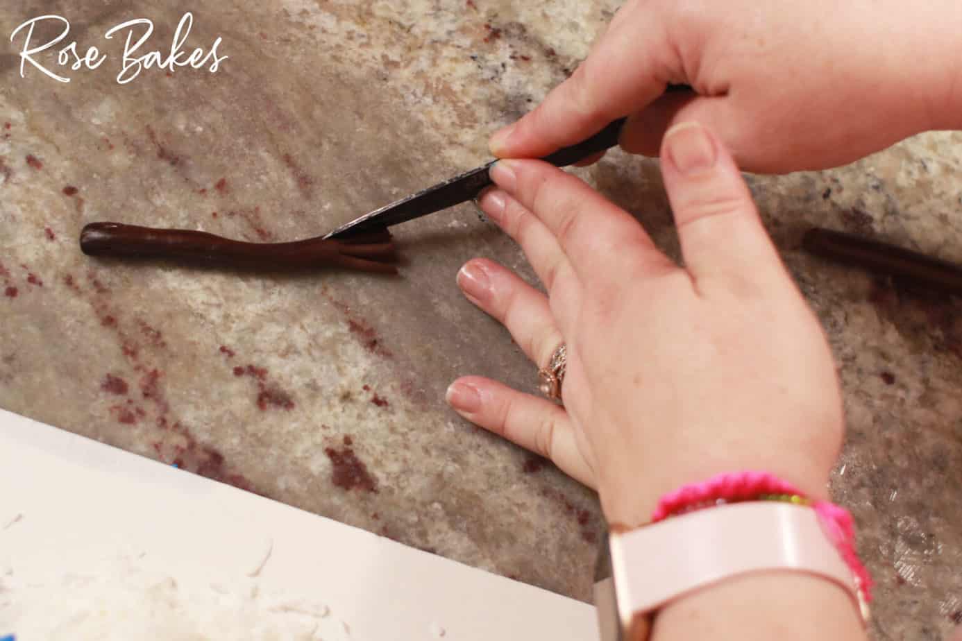 brown fondant being trimmed for snowman honey coconut cake arms