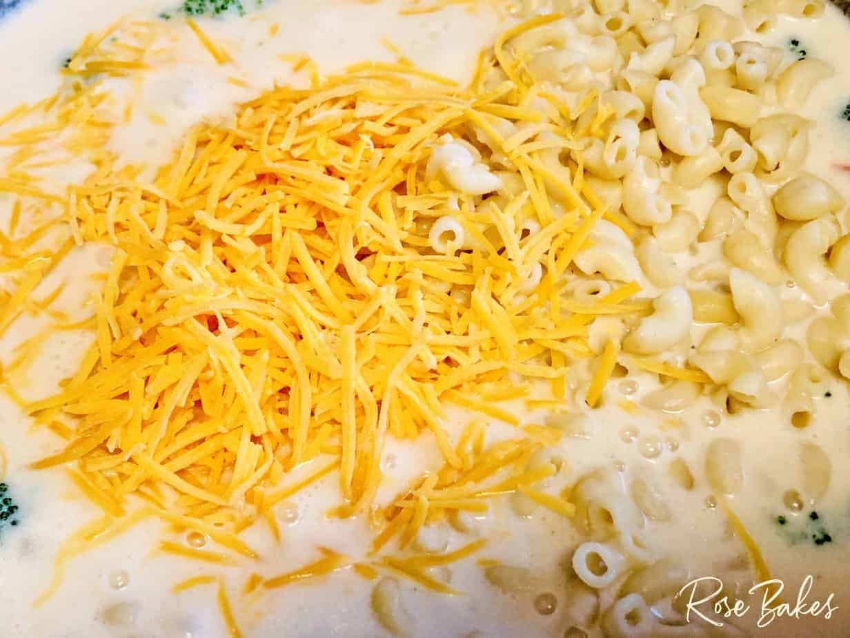 shredded cheese being added to the cooked noodles