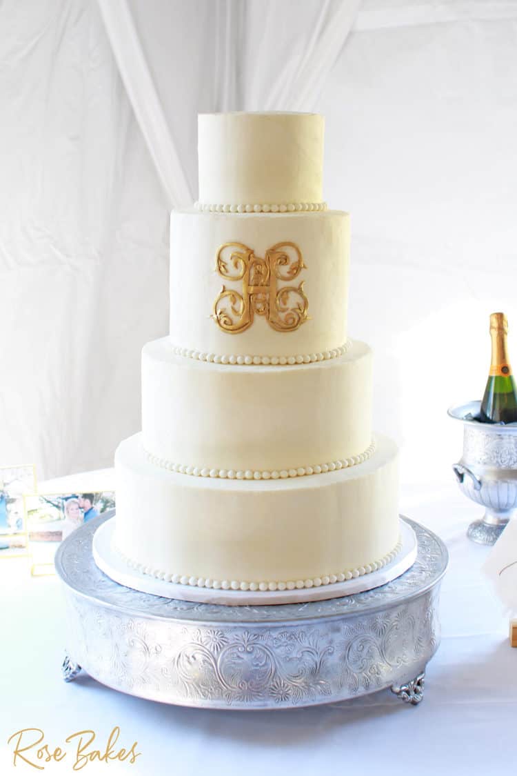 classic white buttercream wedding cake with gold monogram and fondant pearls