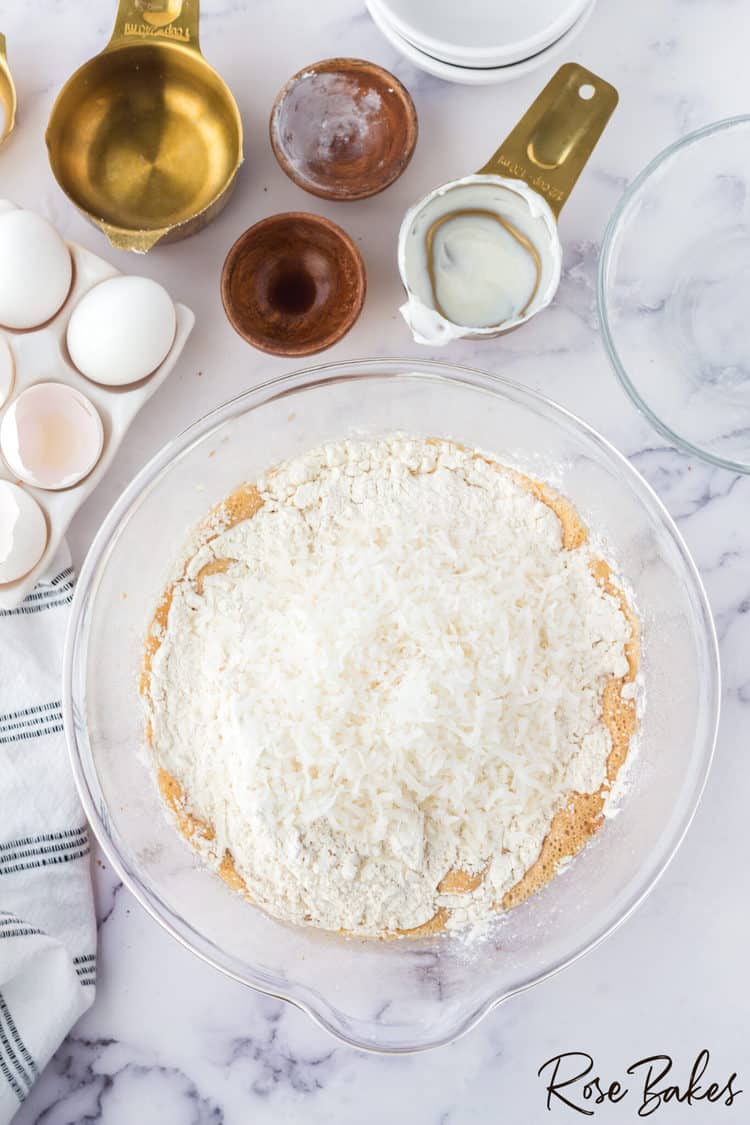 Flour, baking soda, baking powder, and shredded coconut added to the mixing bowl