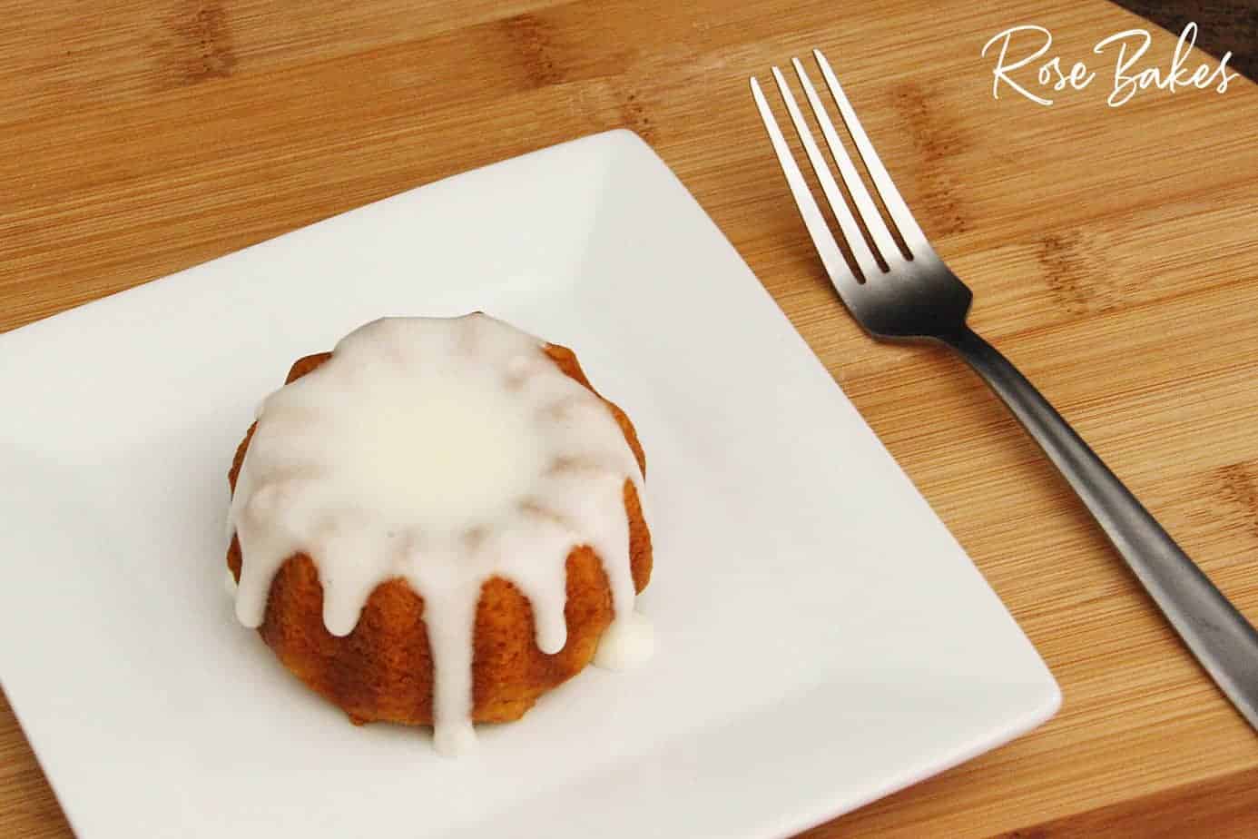 Pumpkin Spice Mini Bundt Cakes a single mini pumpkin spice bundt cake with cream cheese glaze on white square plate