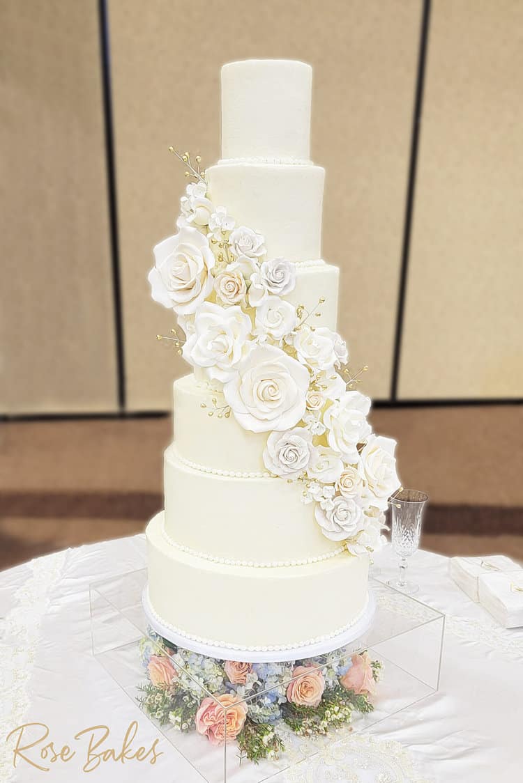 wedding cake with swag of white sugar flowers cascading on buttercream