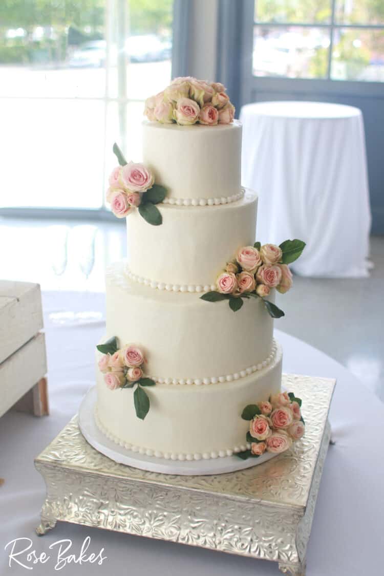 white buttercream wedding cake with pink sweetheart roses and sugar pearls border