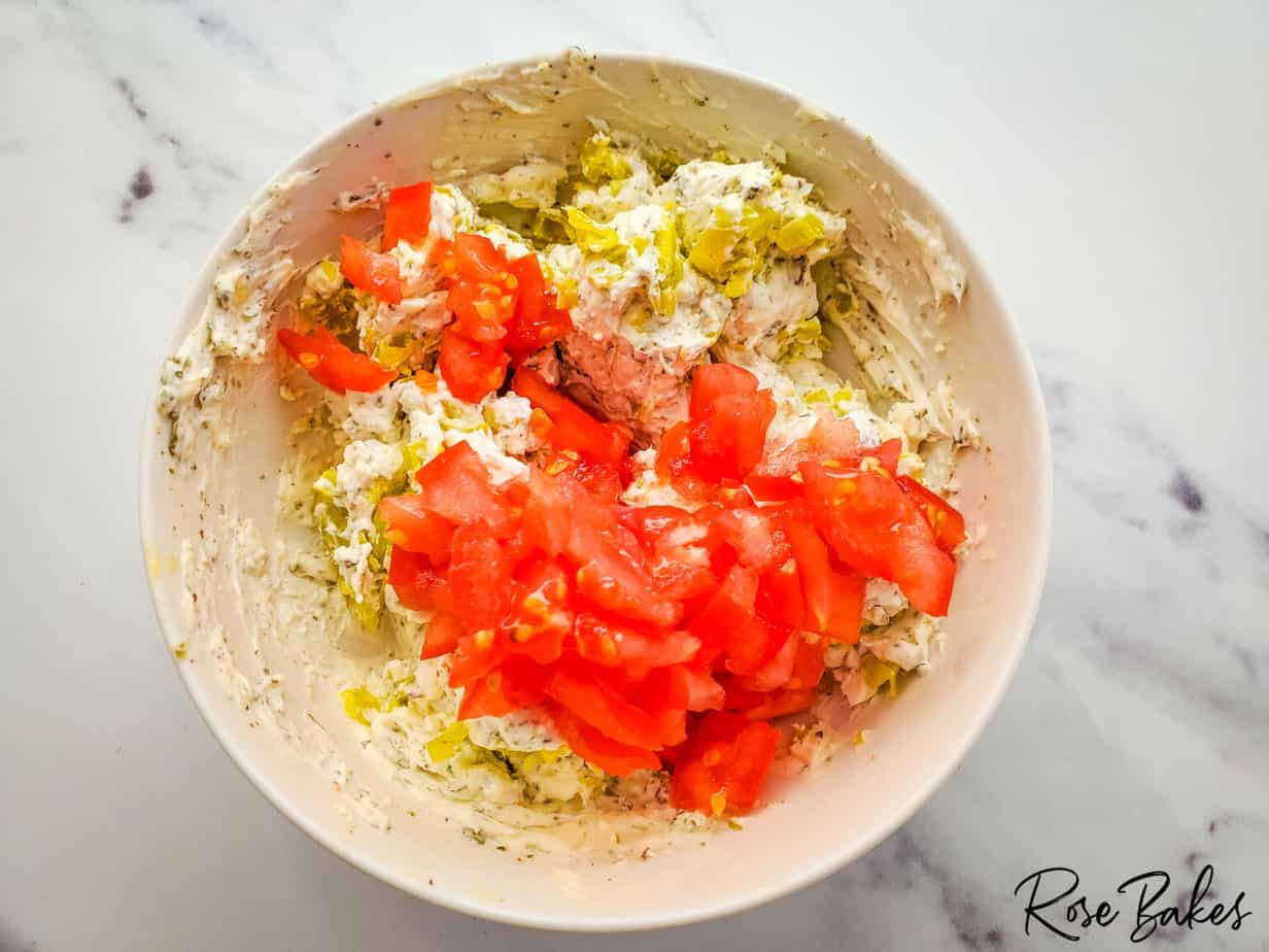 adding diced tomatoes to cream cheese mixture