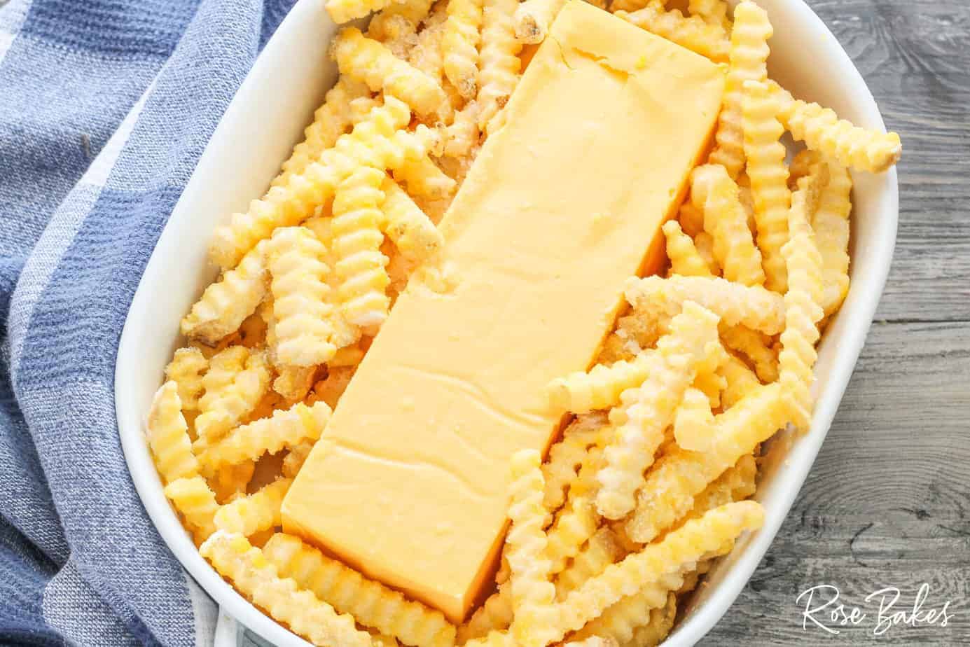 white serving dish with block of velveeta cheese inside with frozen fries around it