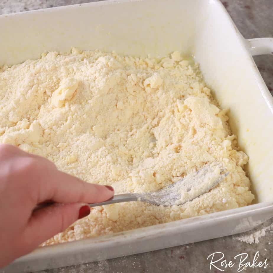 mixture being pressed in to pan with fork