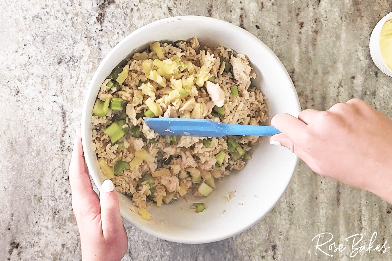 the cooked rice, pineapple, diced celery, and cooked chicken being mixed in a bowl.