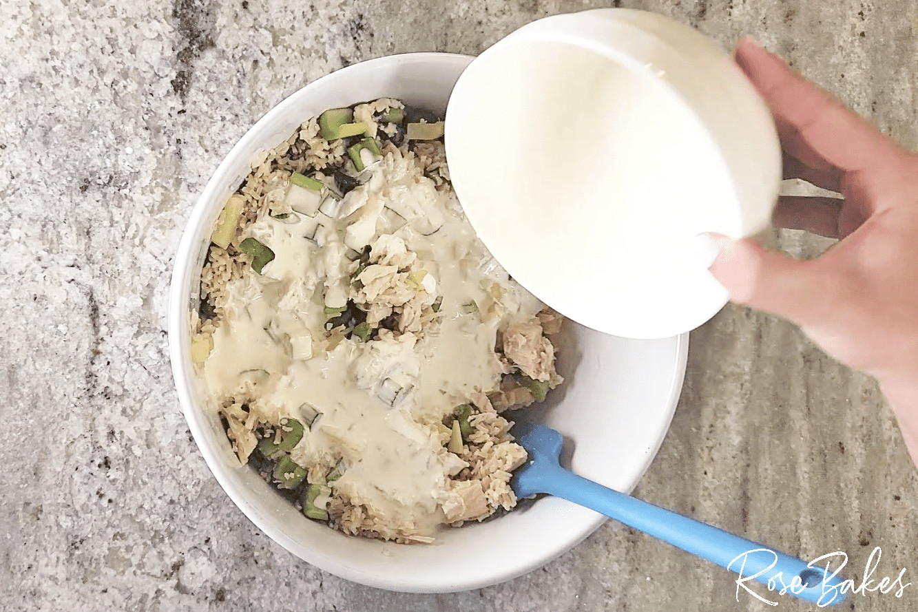 Mayo mixture being poured over the rice mixture.