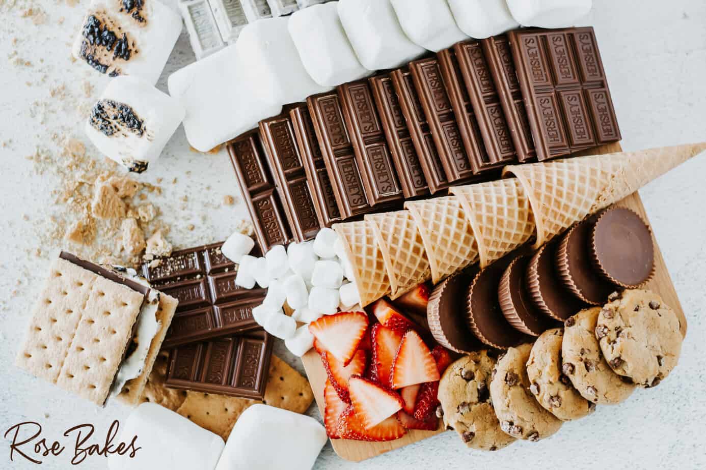 S'mores Dessert Board filled with marshmallows, chocolate bars, graham crackers, cookies strawberries and caramel sauce