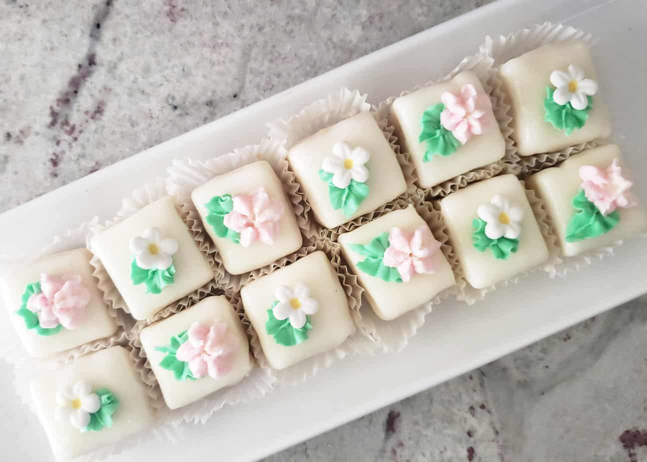 buttercream and royal icing flowers decorating the tops of petit fours