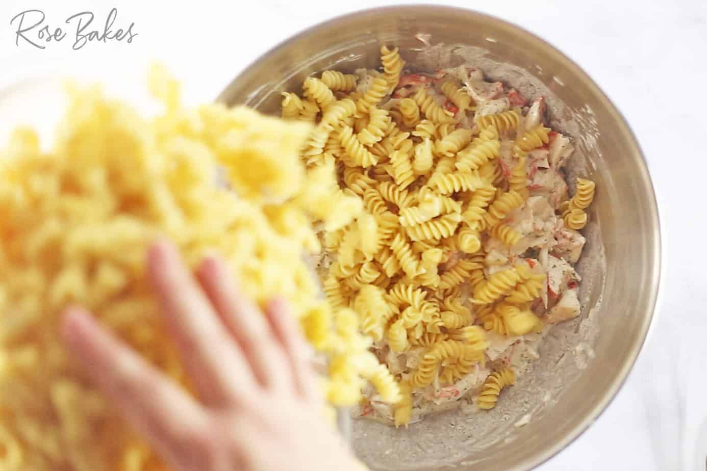 adding cooked pasta to the crab dressing mixture