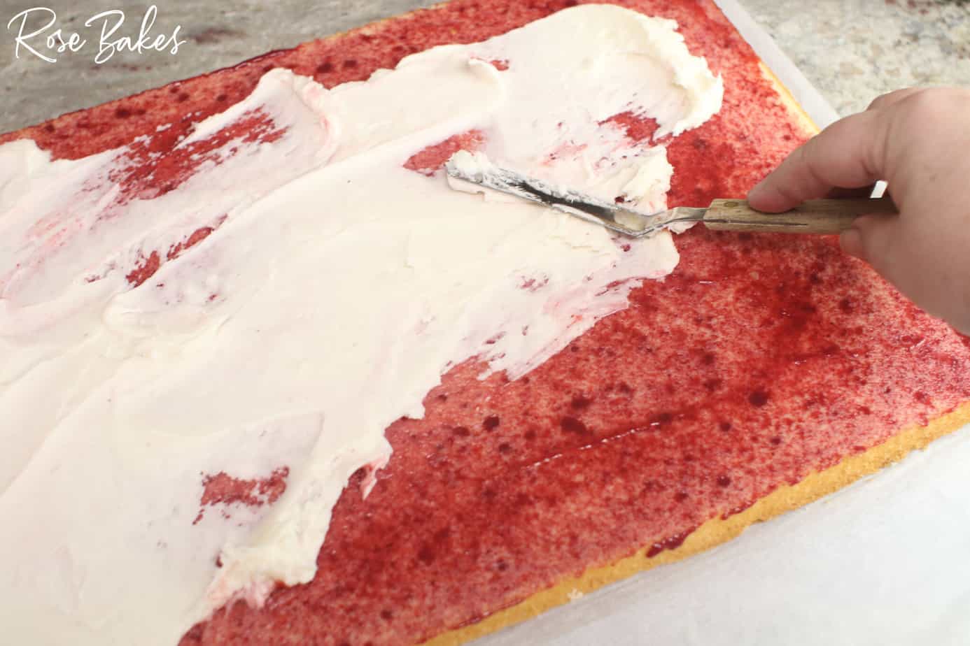 frosting being added on top of the raspberry filling.