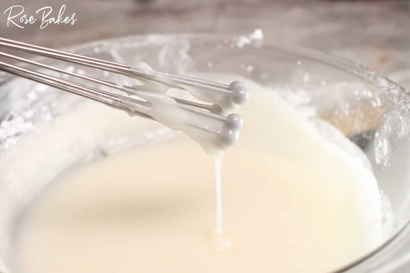Petit Four Icing in a clear bowl mixed with a ball whisk.