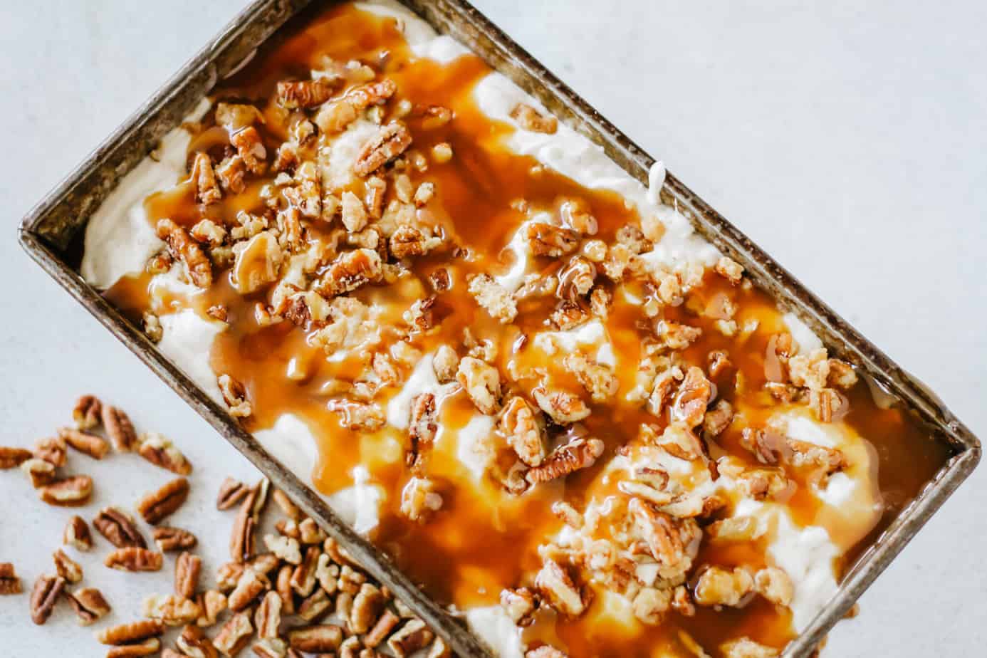 loaf pan of completed pralines and cream ice cream topped with praline pieces and caramel