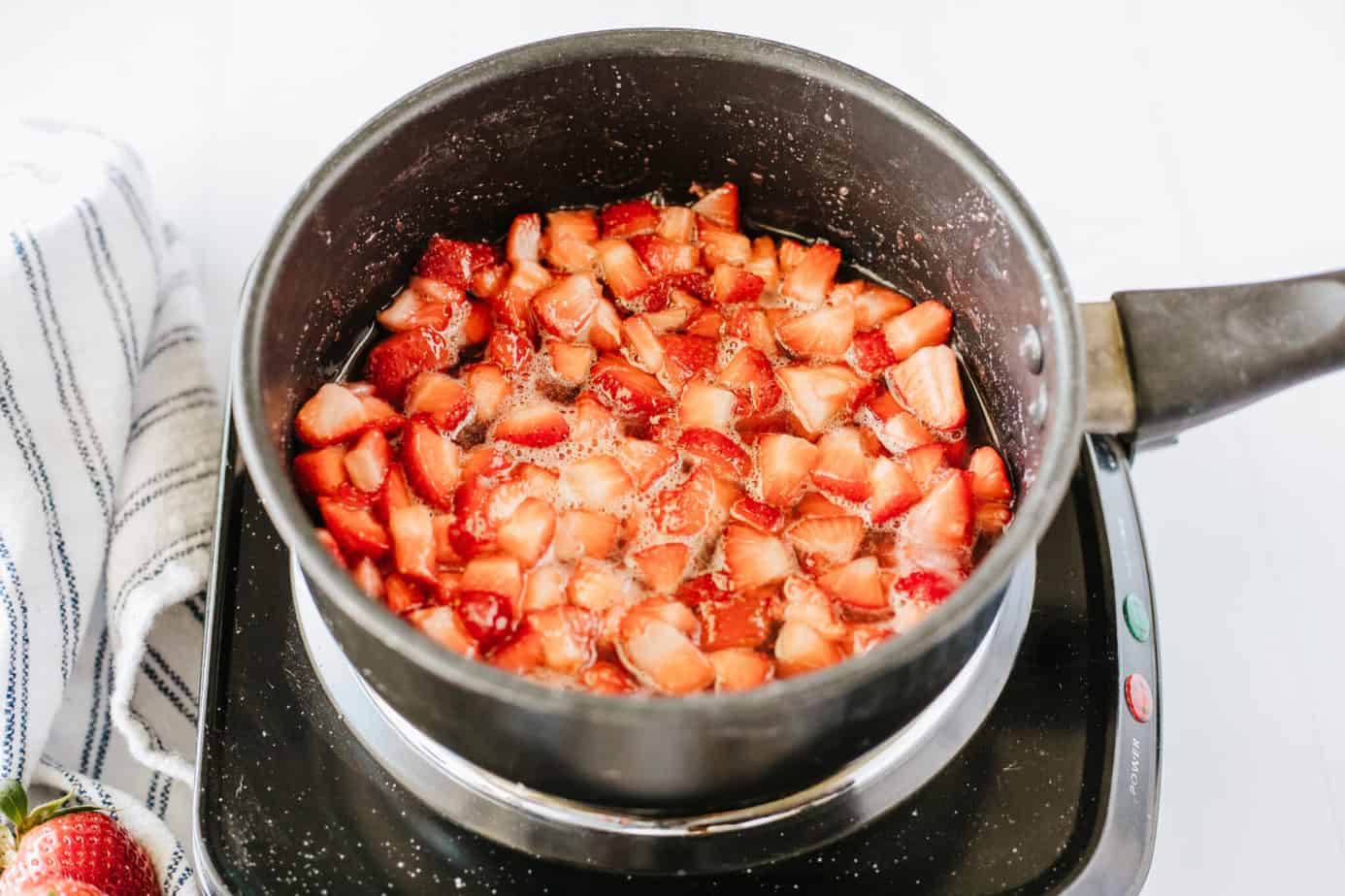 diced strawberries, sugar, lemon juice, vanilla in a boiler on a electric cooktop cooking