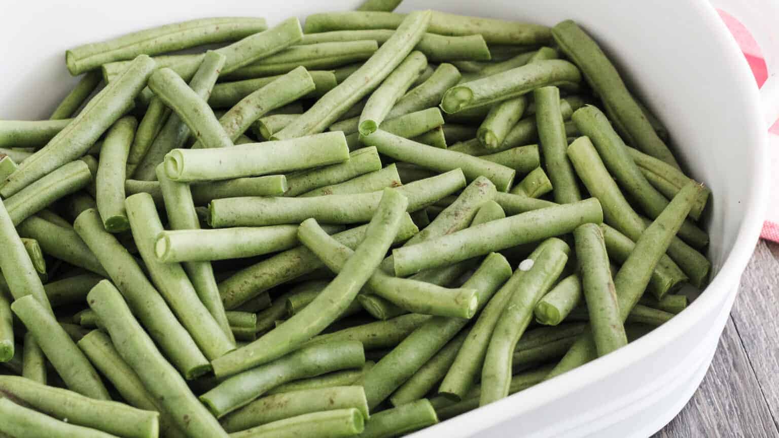 fresh green beans in a white baking dish