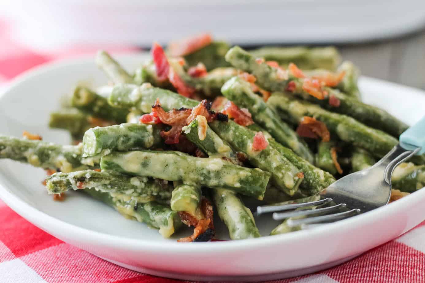 cheesy green bean casserole keto on a white plate with a fork