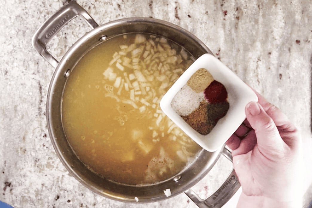 adding spices to soup pot