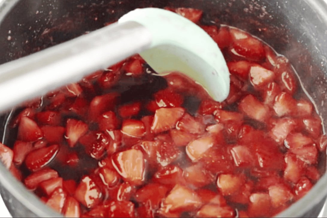 cooking strawberry syrup on a cooktop
