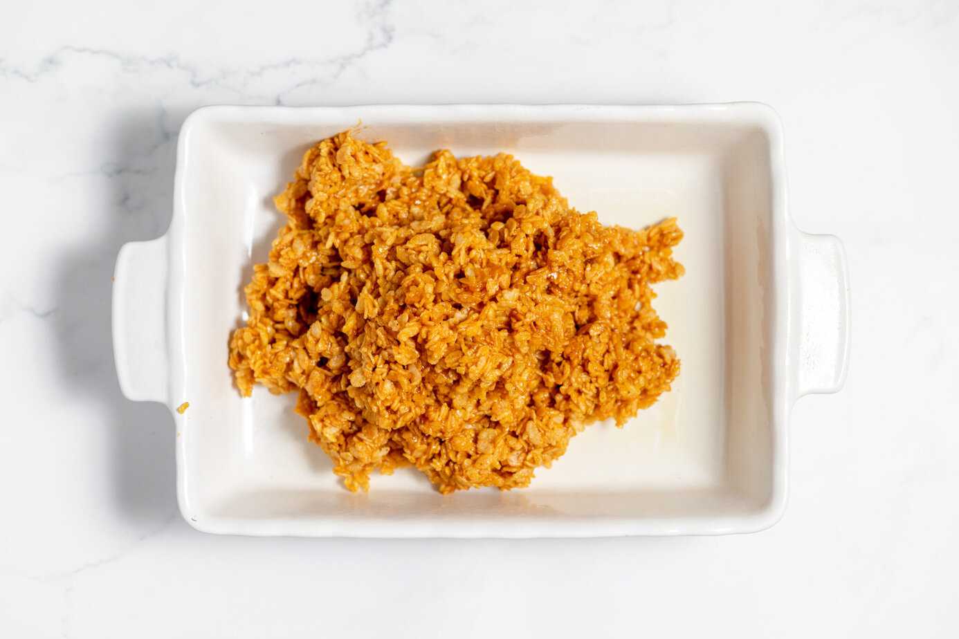 marshmallow and rice cereal mixture poured into white baking dish