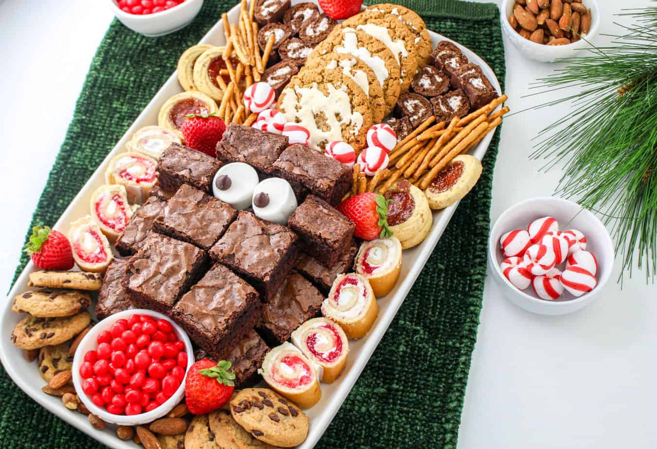 Christmas Dessert Charcuterie Board: on a green towel surrounded by bowls of candy and nuts