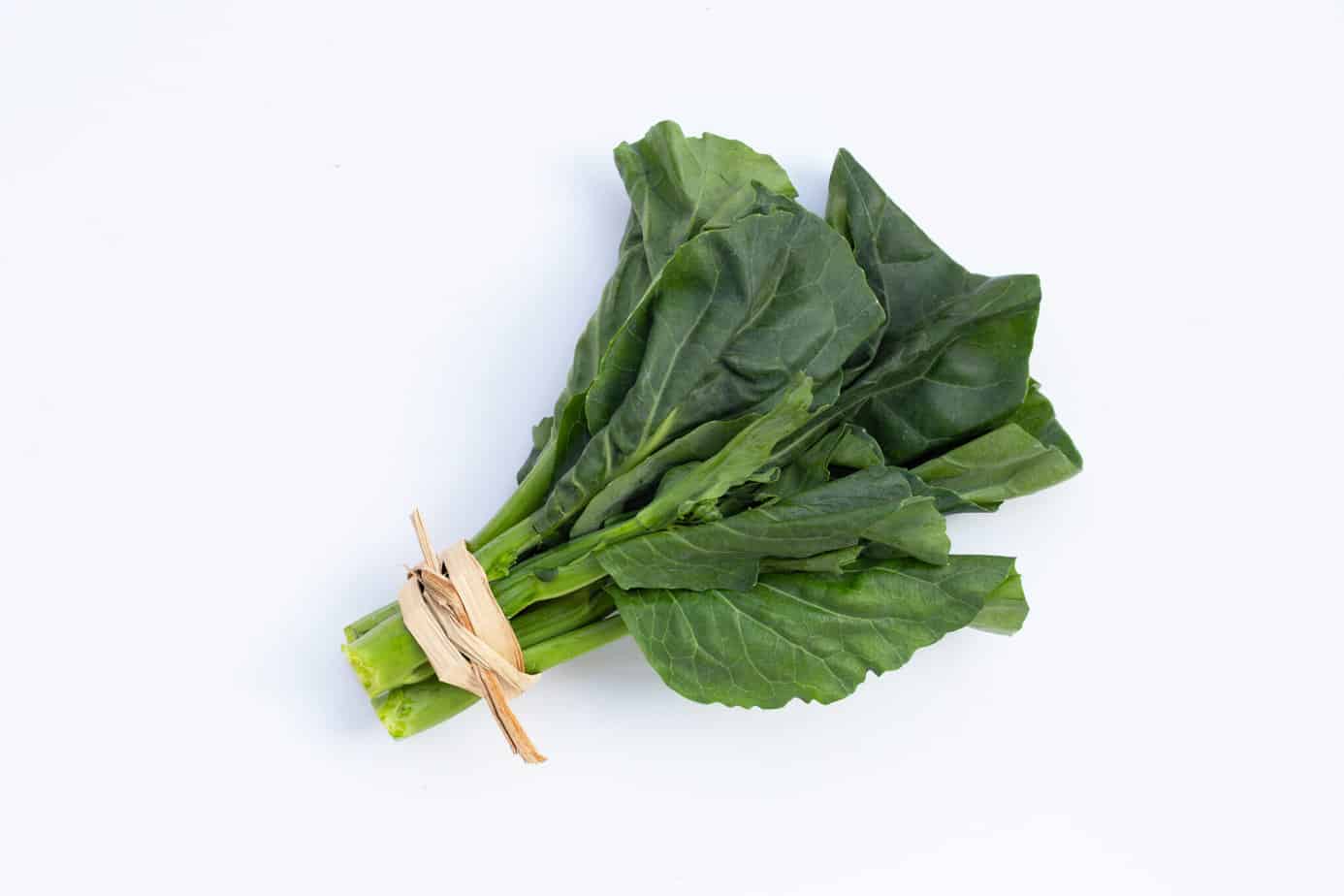 a bunch of fresh collard greens on a white surface