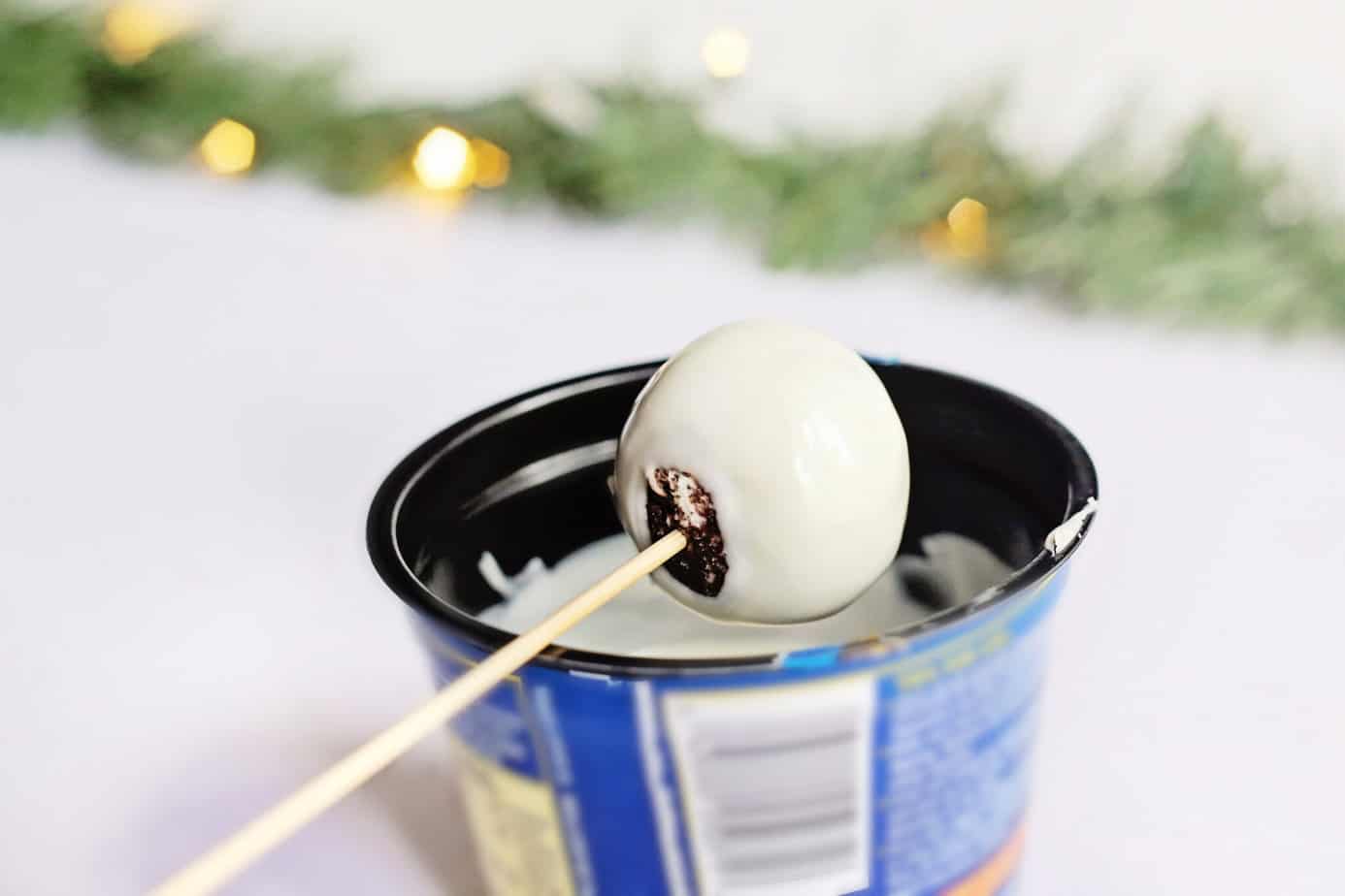 dipping a Little Debbie Christmas Tree Cake Truffle in white chocolate