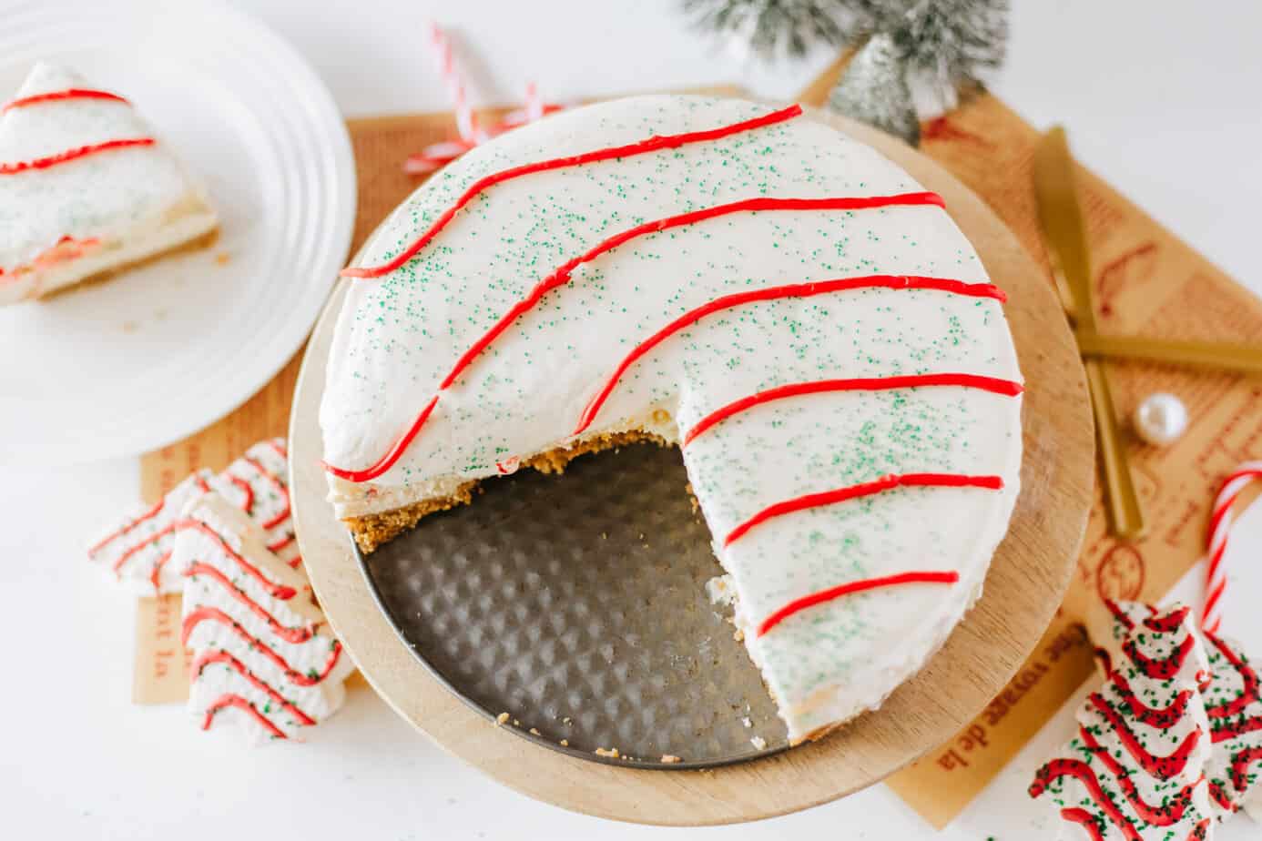 Little Debbie Christmas Tree Cake Cheesecake on a wooden stand with slices cut out