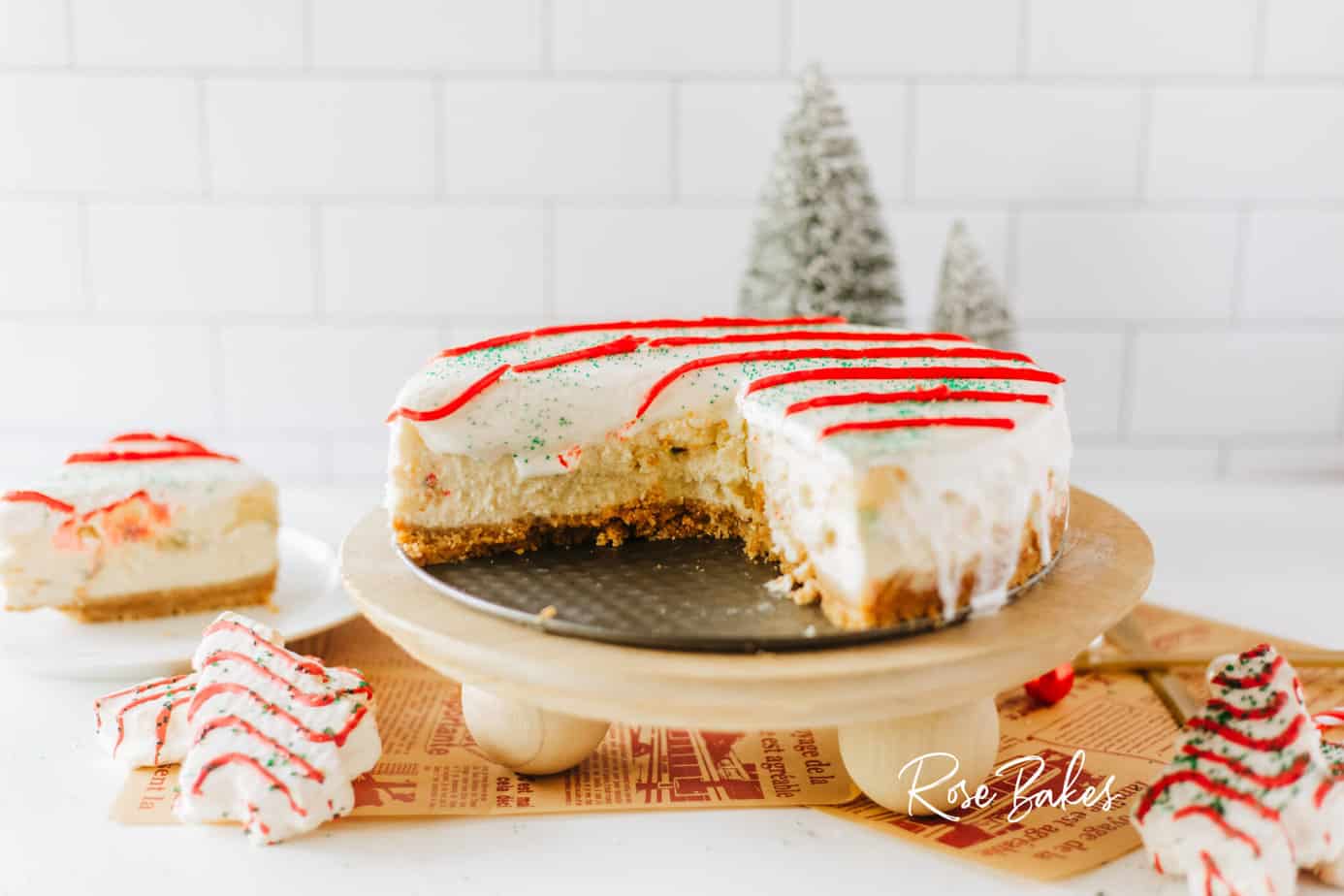 Sliced Little Debbie Christmas Tree Cheesecake on a wooden stand with christmas tree cakes laying around it