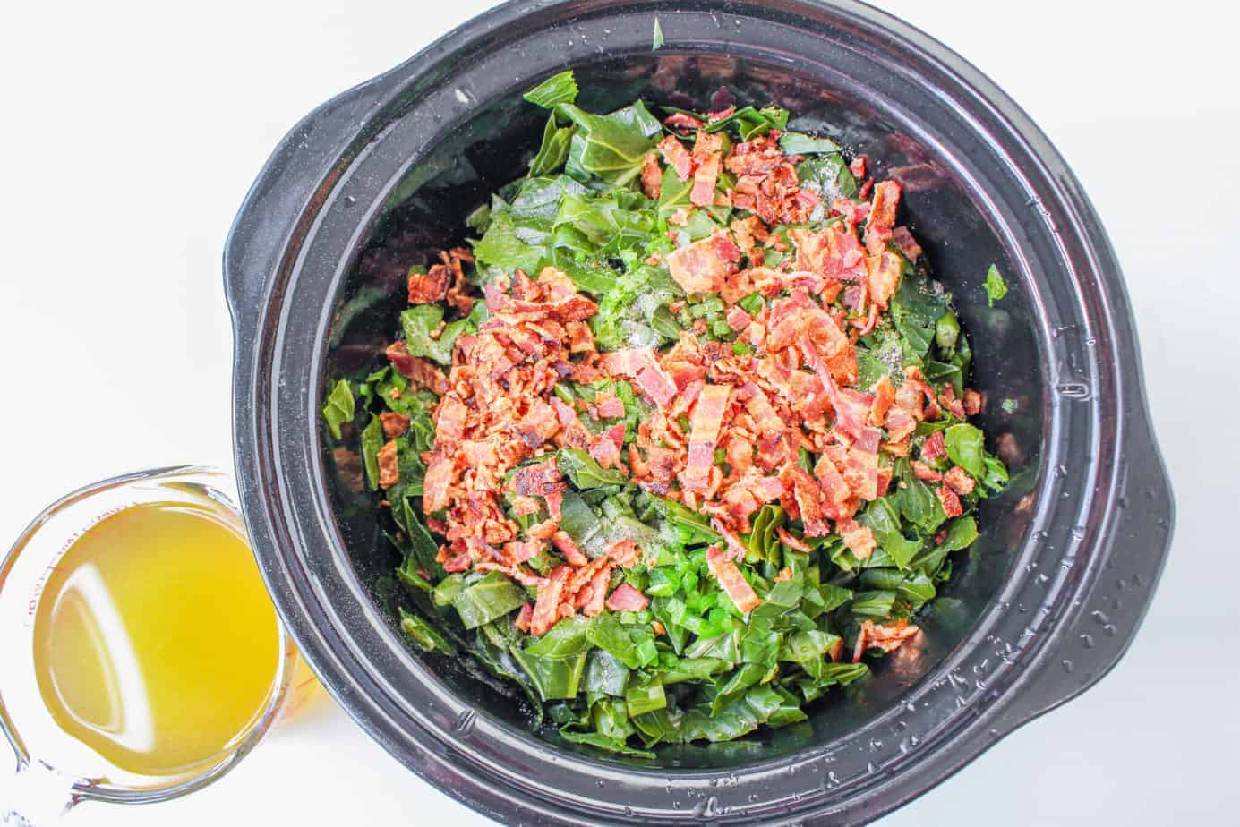 fresh collard greens in a slow cooker with bacon pieces