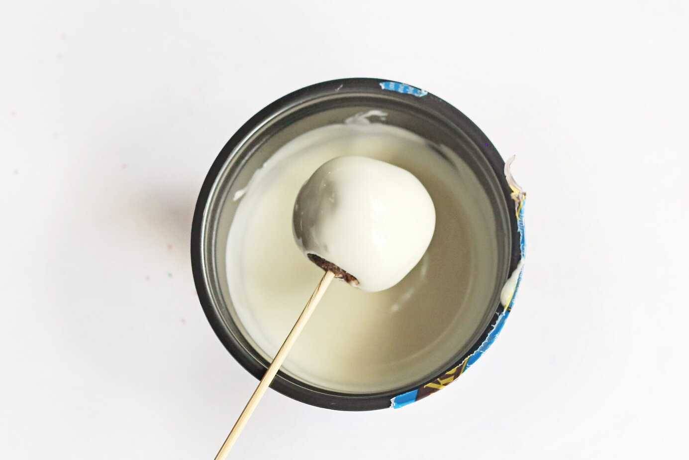 dipping a Little Debbie Christmas Tree Cake Truffle in white chocolate on a bamboo skewer
