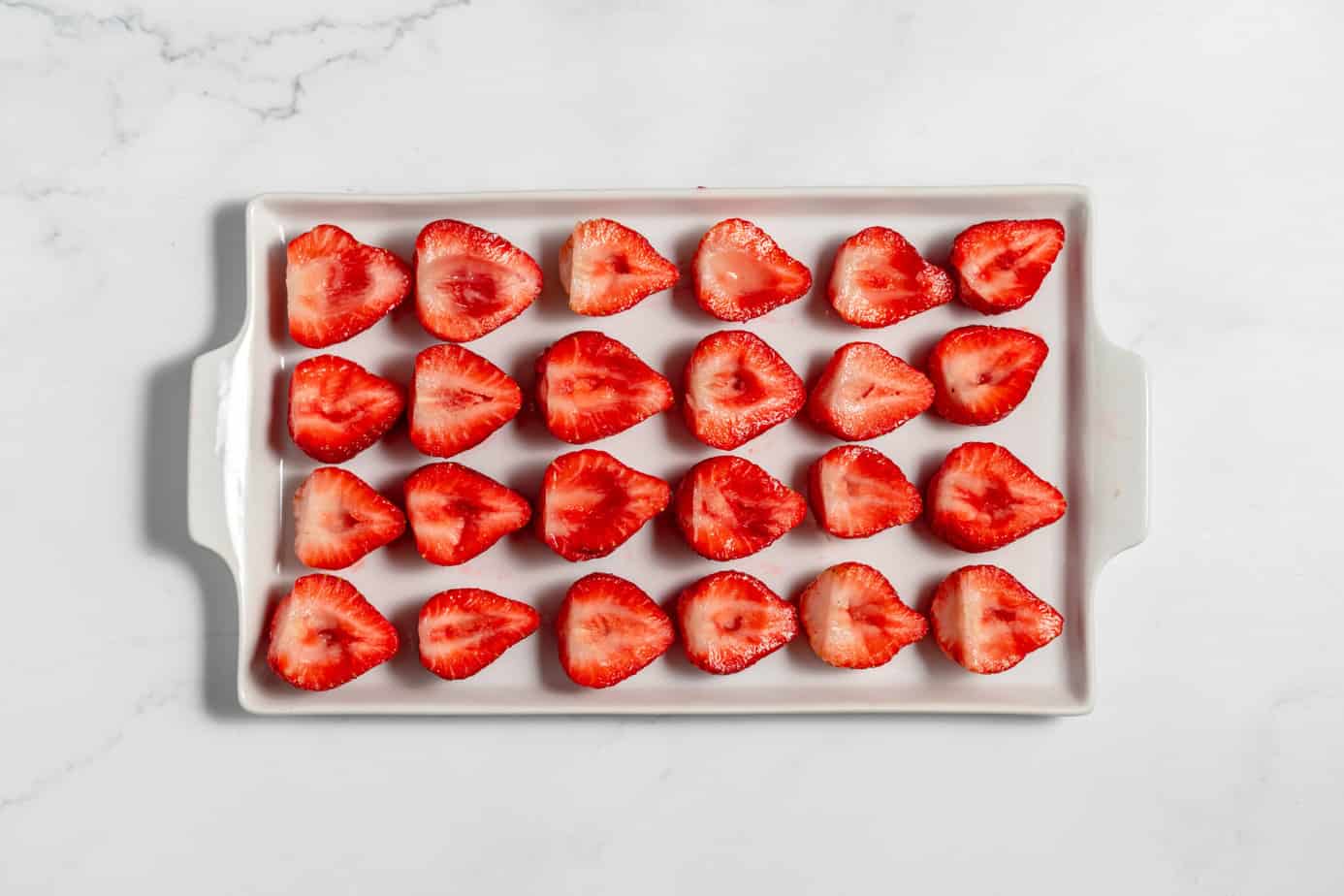 halved strawberries on a white platter