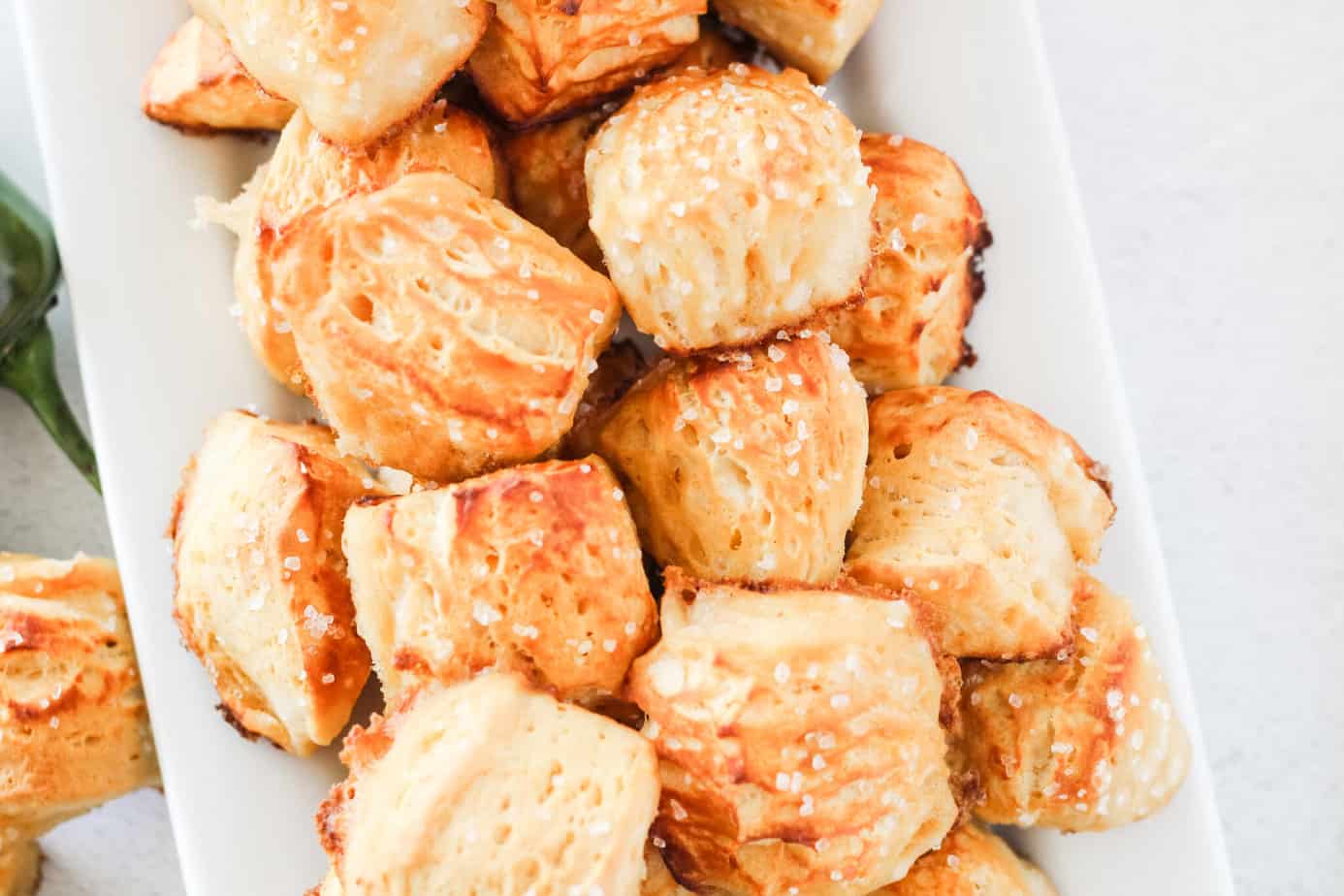 biscuit pretzel bites on a white platter with sea salt over them