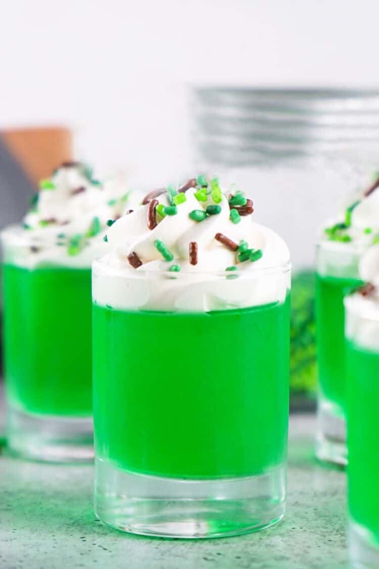 green jello shots with whipped cream and sprinkles
