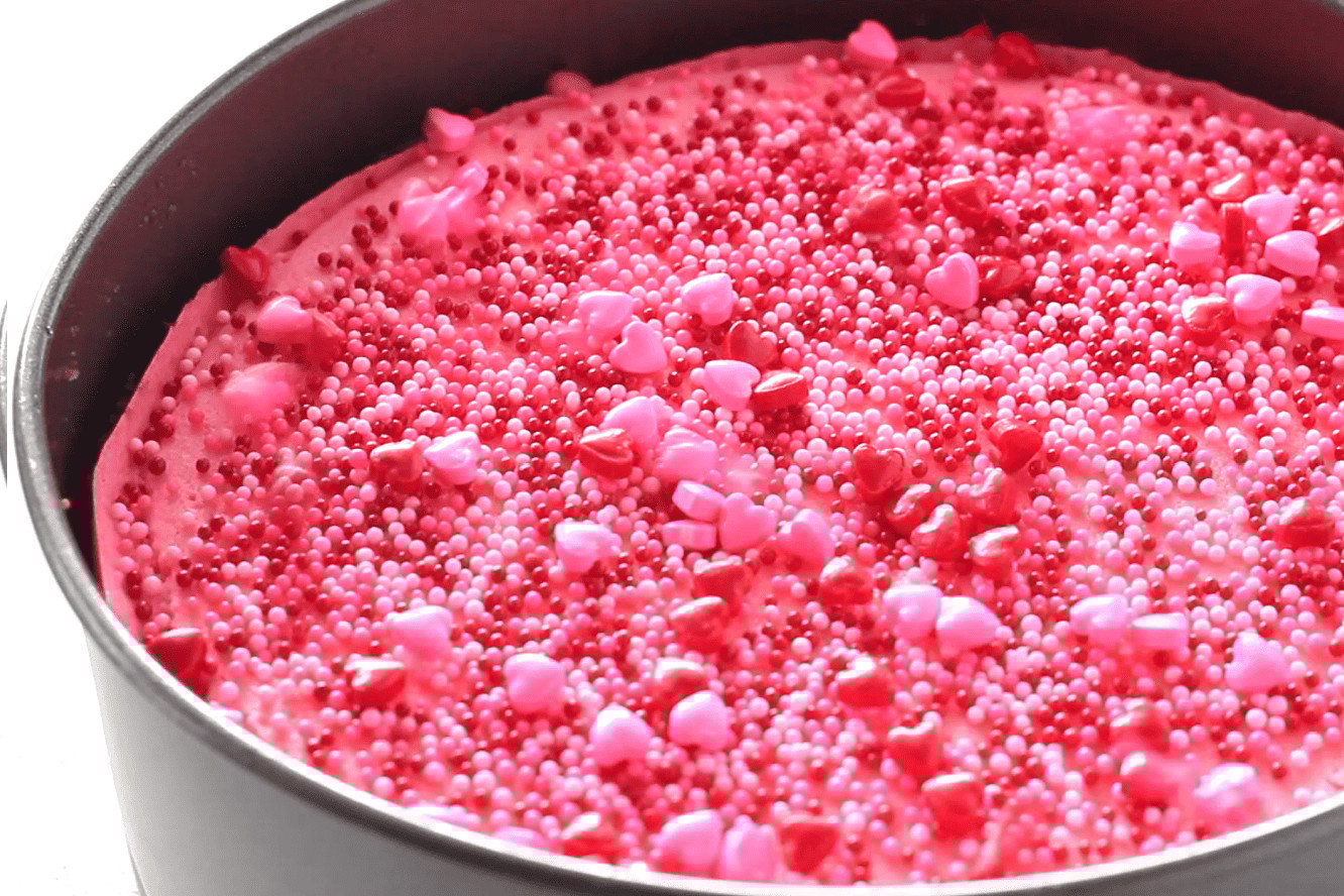 hot pink valentine's day cheesecake with red pink and white sprinkles in the springform pan