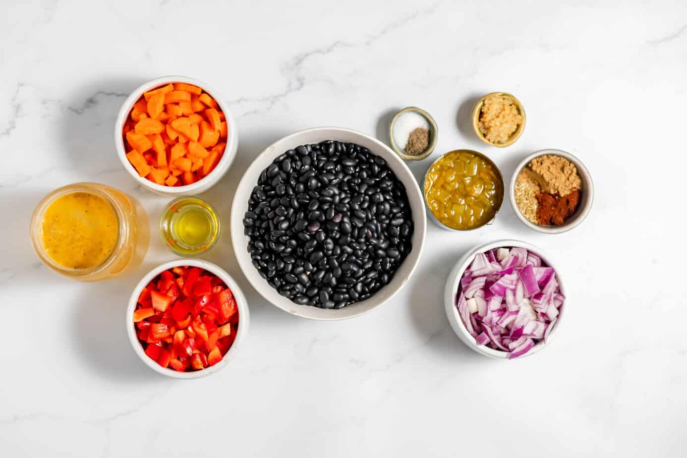 instant pot black bean soup ingredients in white bowls on marble surface