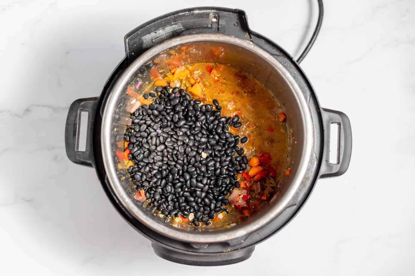 peppers onions and carrots in instant pot with seasonings and black beans added