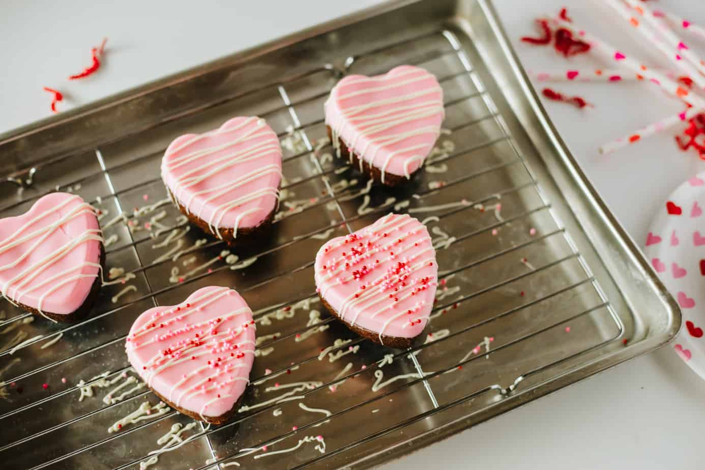 drizzled white chocolate and sprinkles over Heart Brownies on a wire rack with pink chocolate on top