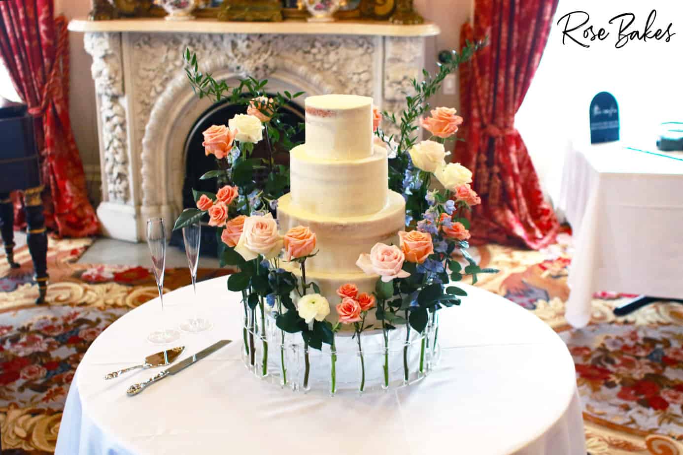 Three tier wedding cake with lots of flowers around it